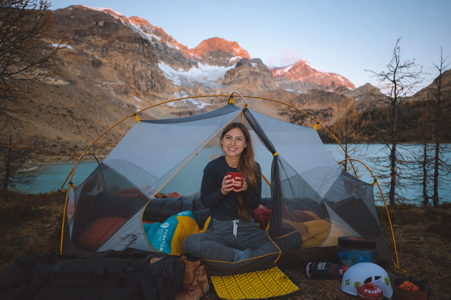 Rowan with a mug beside a tent and mountain lake